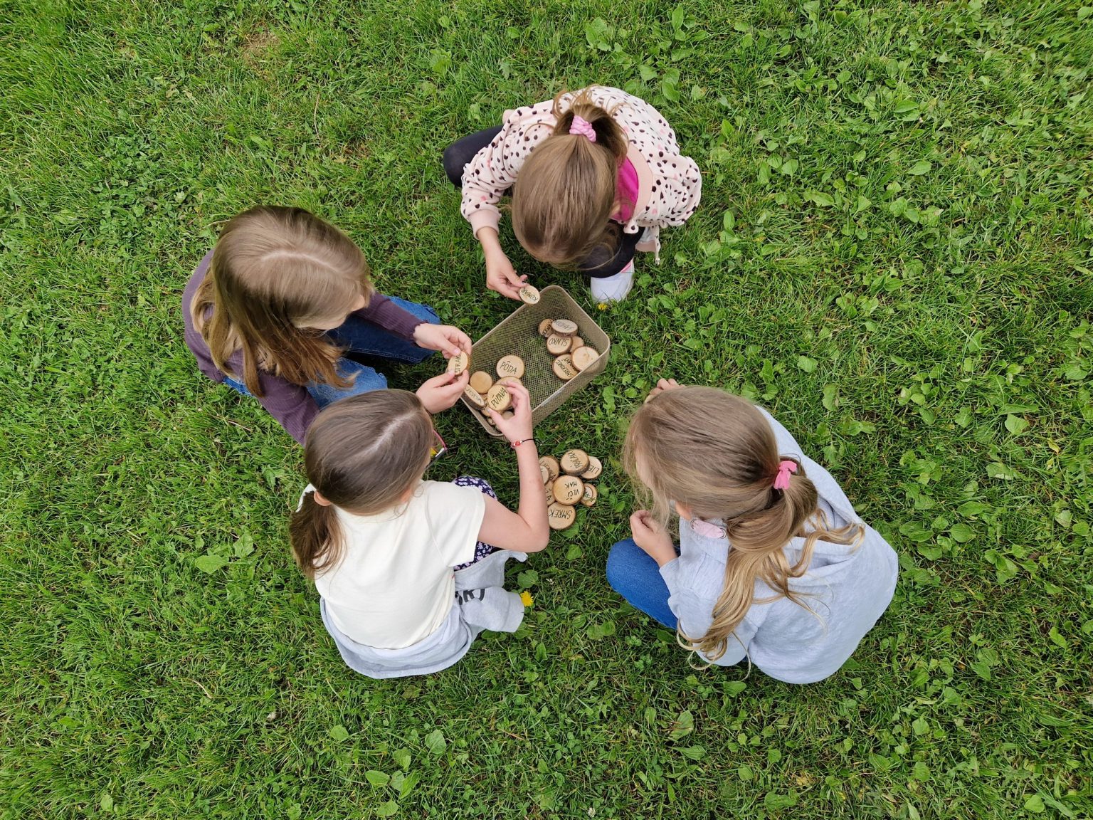 štyri deti kvočia nad boxom s drevenými písmenkami.