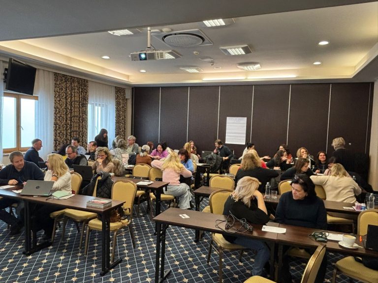 Lektori a lektorky sa vzdelávajú spoločne sedia za stolmi a diskutujú.