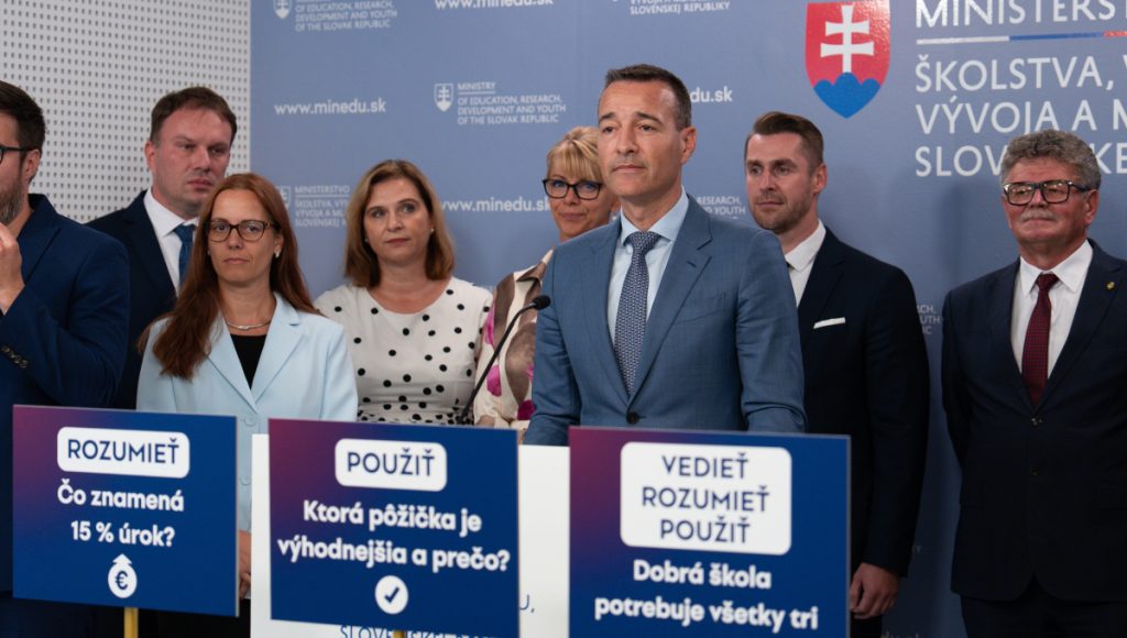 Na fotografii stoja ľudia za ministrom školstva Tomášom Druckerom, ktorý stojí za rečníckym pultom na tlačovej besede.